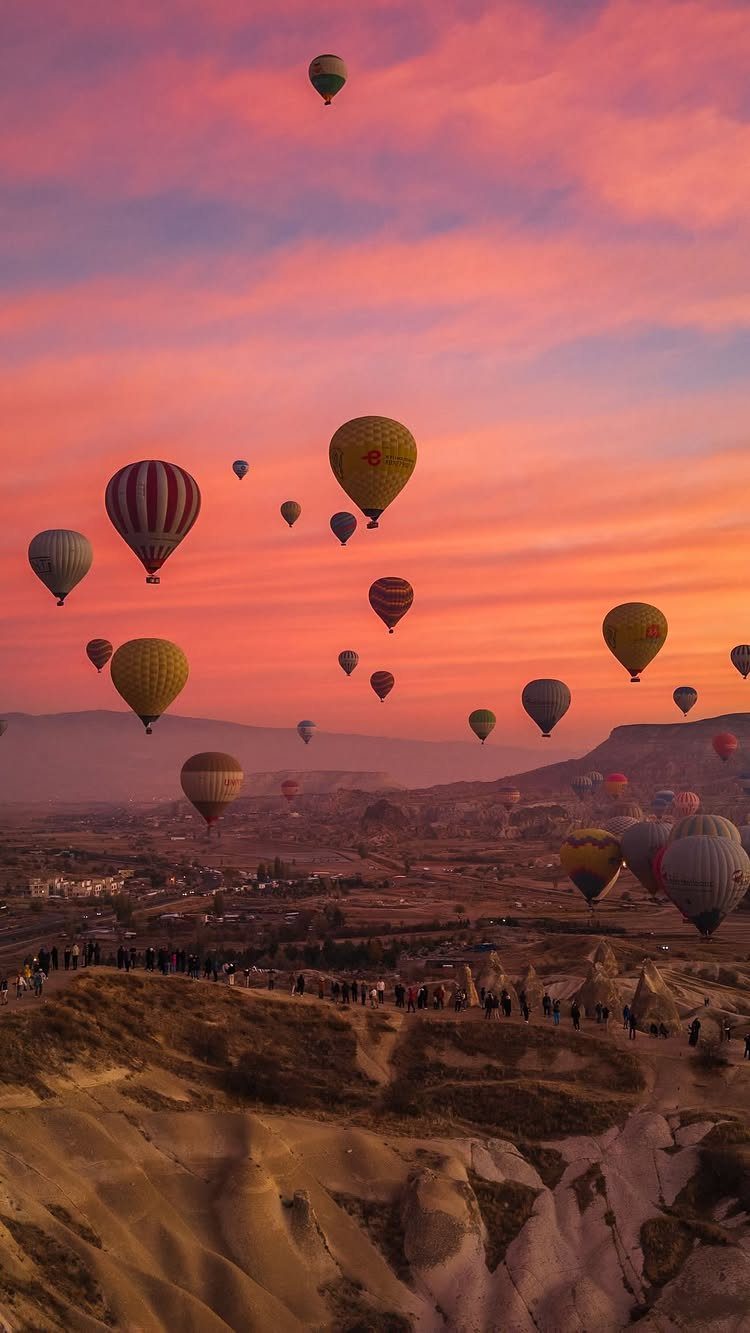 Colorful hot air balloons floating over the unique rock formations of Cappadocia at sunrise.