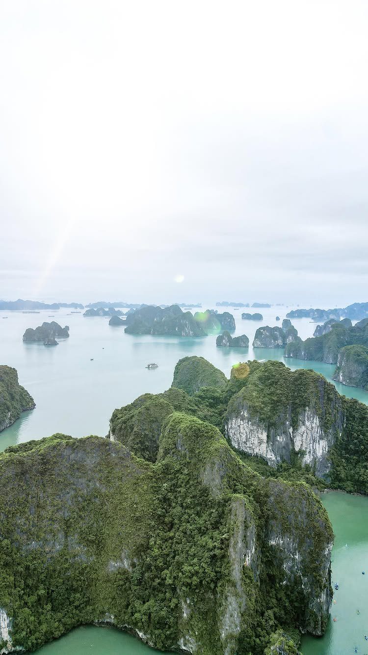 Green limestone karst islands rising from turquoise waters in Ha Long Bay.