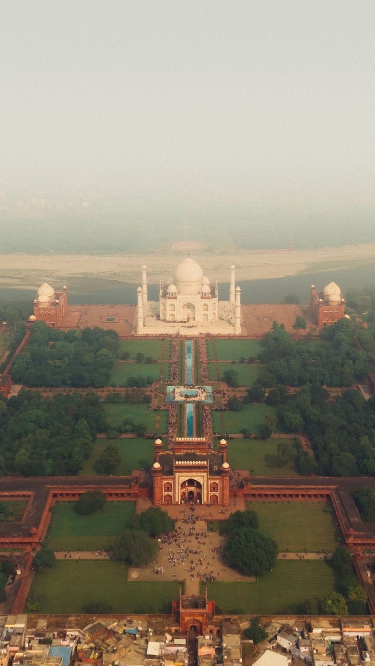 The white marble Taj Mahal mausoleum centered within symmetrical gardens and reflecting pools.