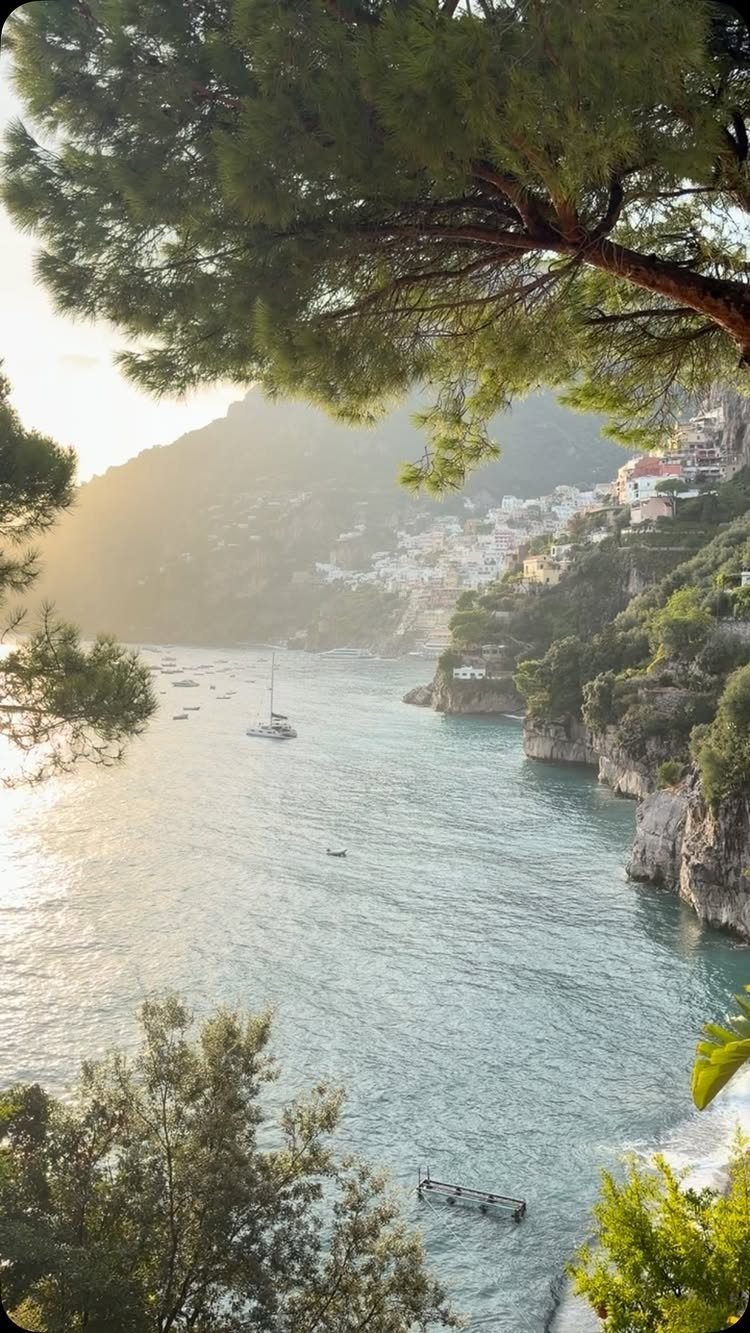Coastal town with white buildings on a cliff overlooking a turquoise bay.