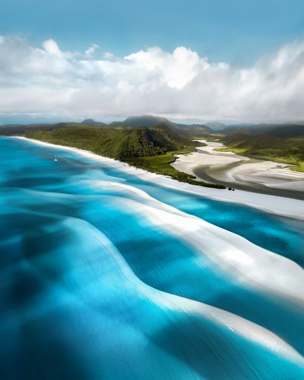 Swirling white sands and turquoise waters along a lush tropical coastline.