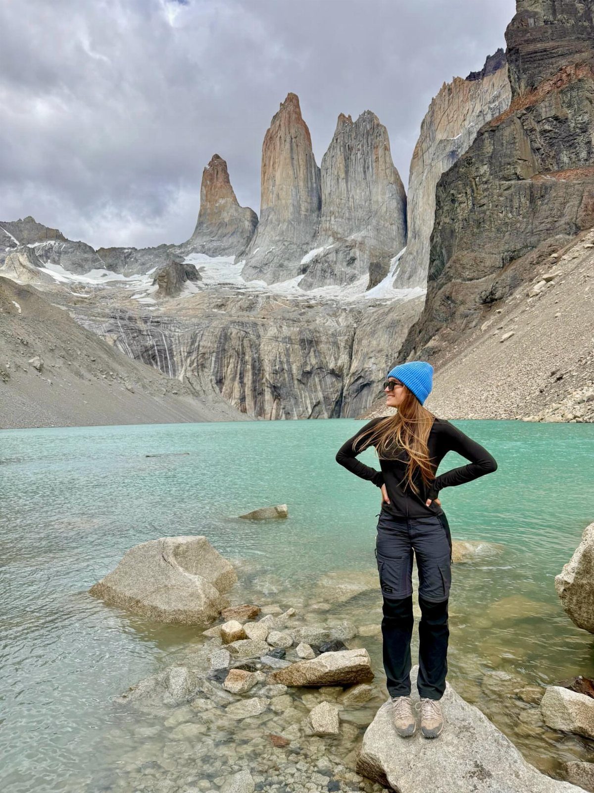 16 Adventurous Places to Travel, From Utah to Mongolia 10 Woman standing by a turquoise lake with towering granite peaks in Chile