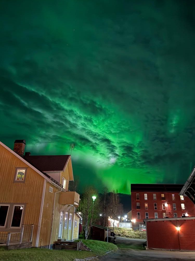 16 Adventurous Places to Travel, From Utah to Mongolia 6 Green aurora borealis glowing in the night sky over colorful wooden village houses.
