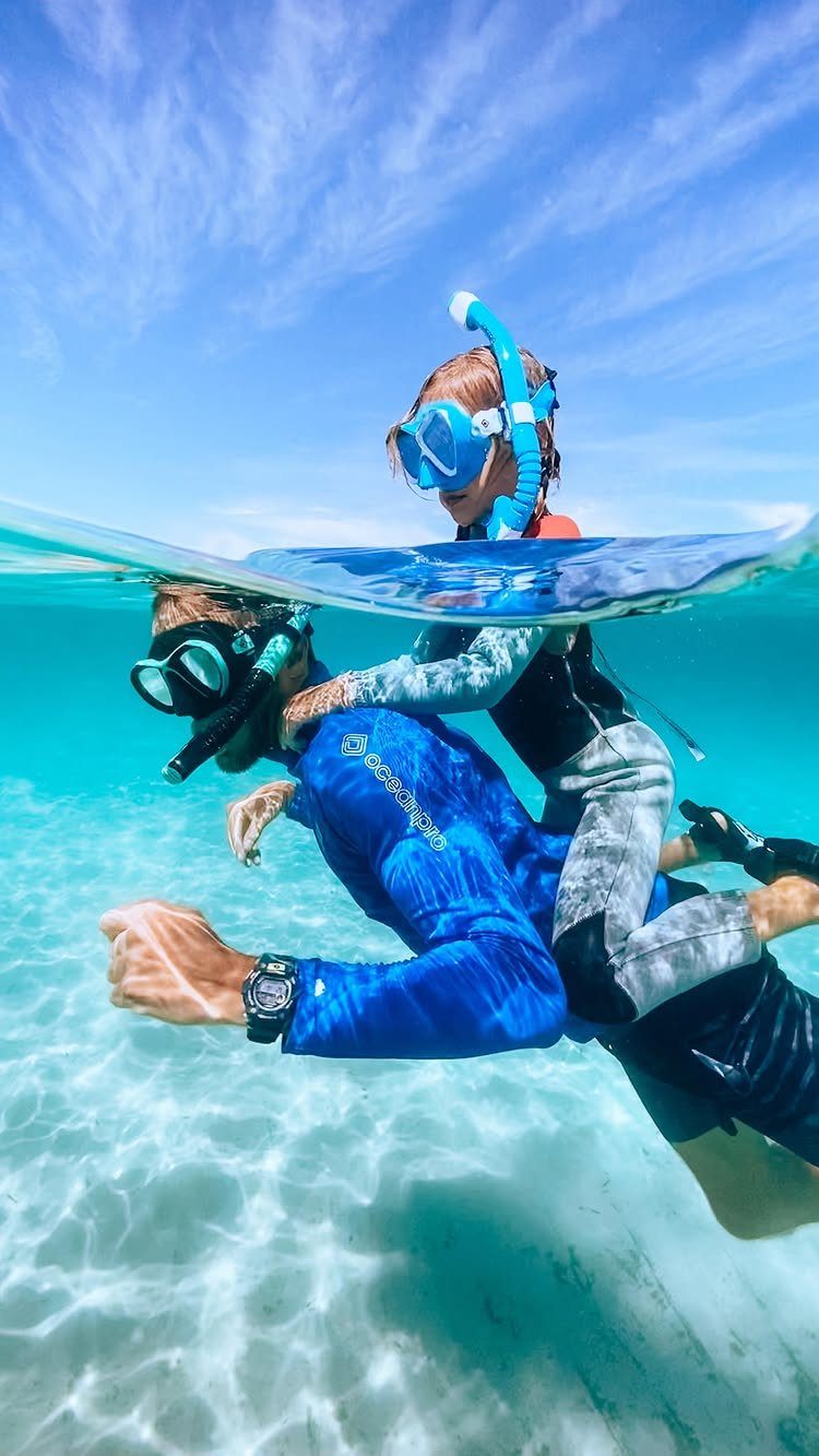 16 Adventurous Places to Travel, From Utah to Mongolia 12 Man and child snorkeling in clear turquoise tropical water with a split-level view.