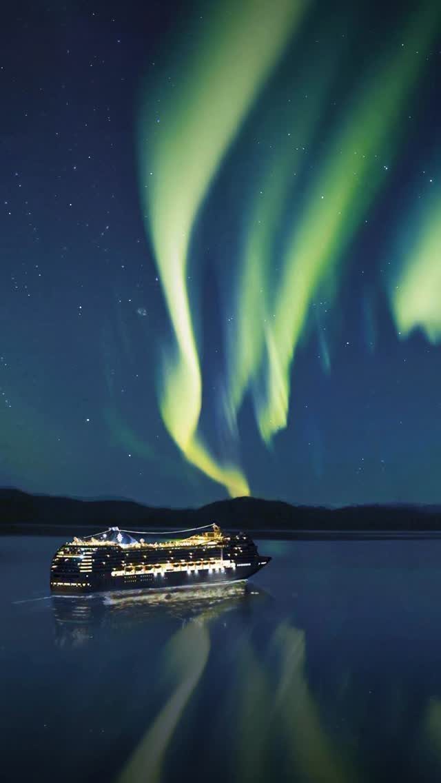 Cruise ship sailing on calm water under vibrant green aurora borealis night sky