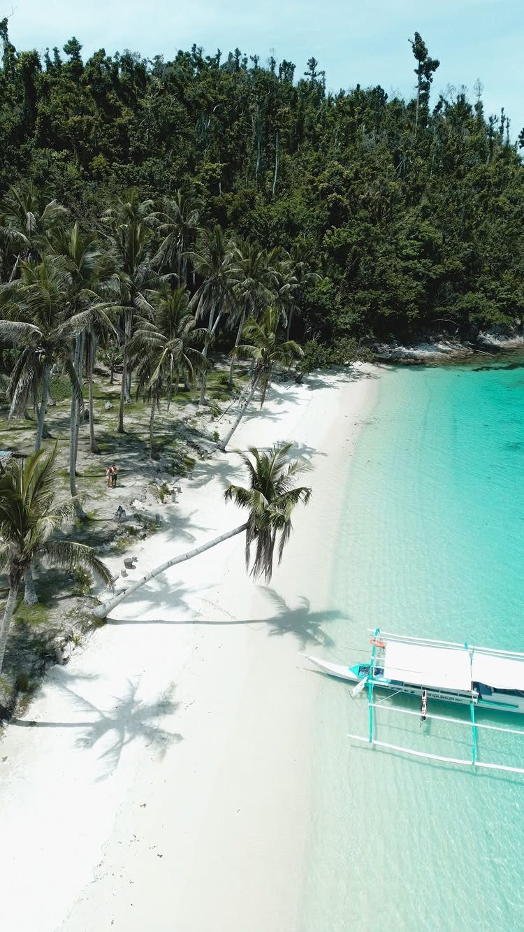 Beach Places to Travel: 13 Ideas for Your Next Trip 8 White sandy beach with turquoise water, palm trees, and a traditional outrigger boat.