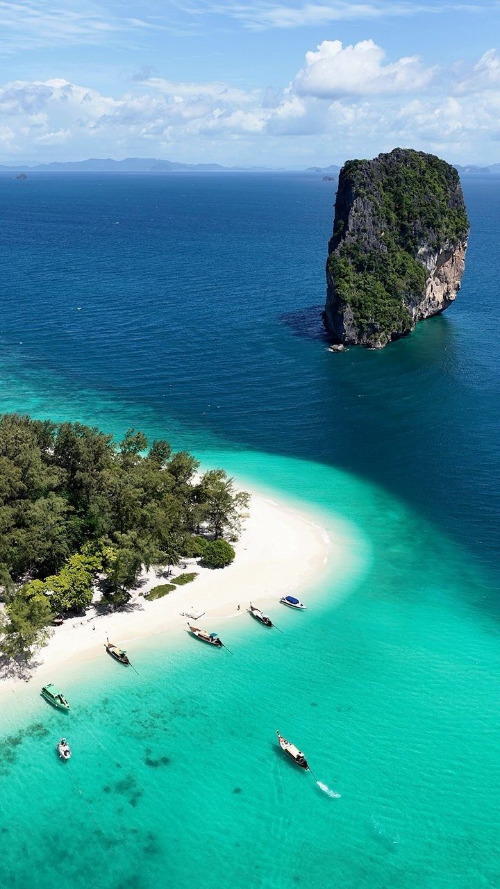 Beach Places to Travel: 13 Ideas for Your Next Trip 5 White sand beach with turquoise water and a large limestone cliff in Thailand.