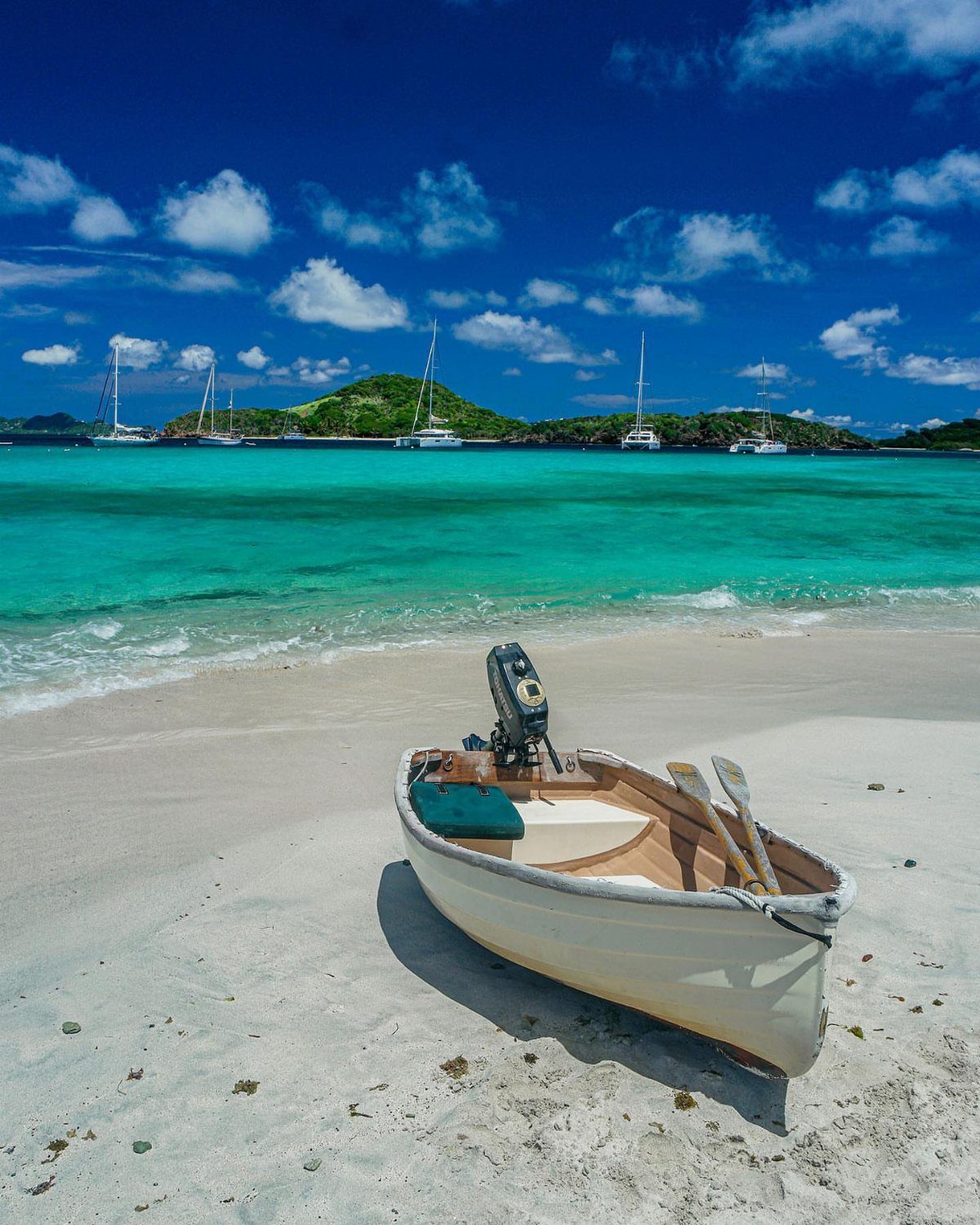 Beach Places to Travel: 13 Ideas for Your Next Trip 11 White motorboat on a sandy beach with turquoise water and distant islands.