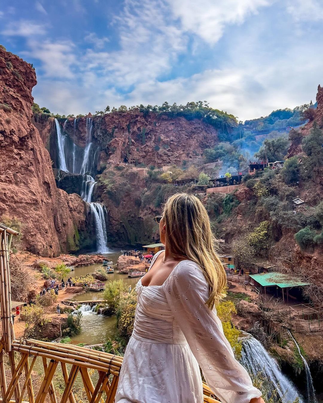Woman in white dress overlooking the cascading Ouzoud Waterfalls in Morocco.