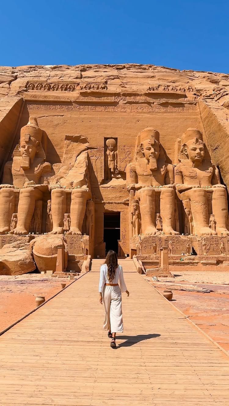 28 Beautiful Places to Travel Around the World 5 Woman walking toward the giant carved sandstone statues of Abu Simbel temple.