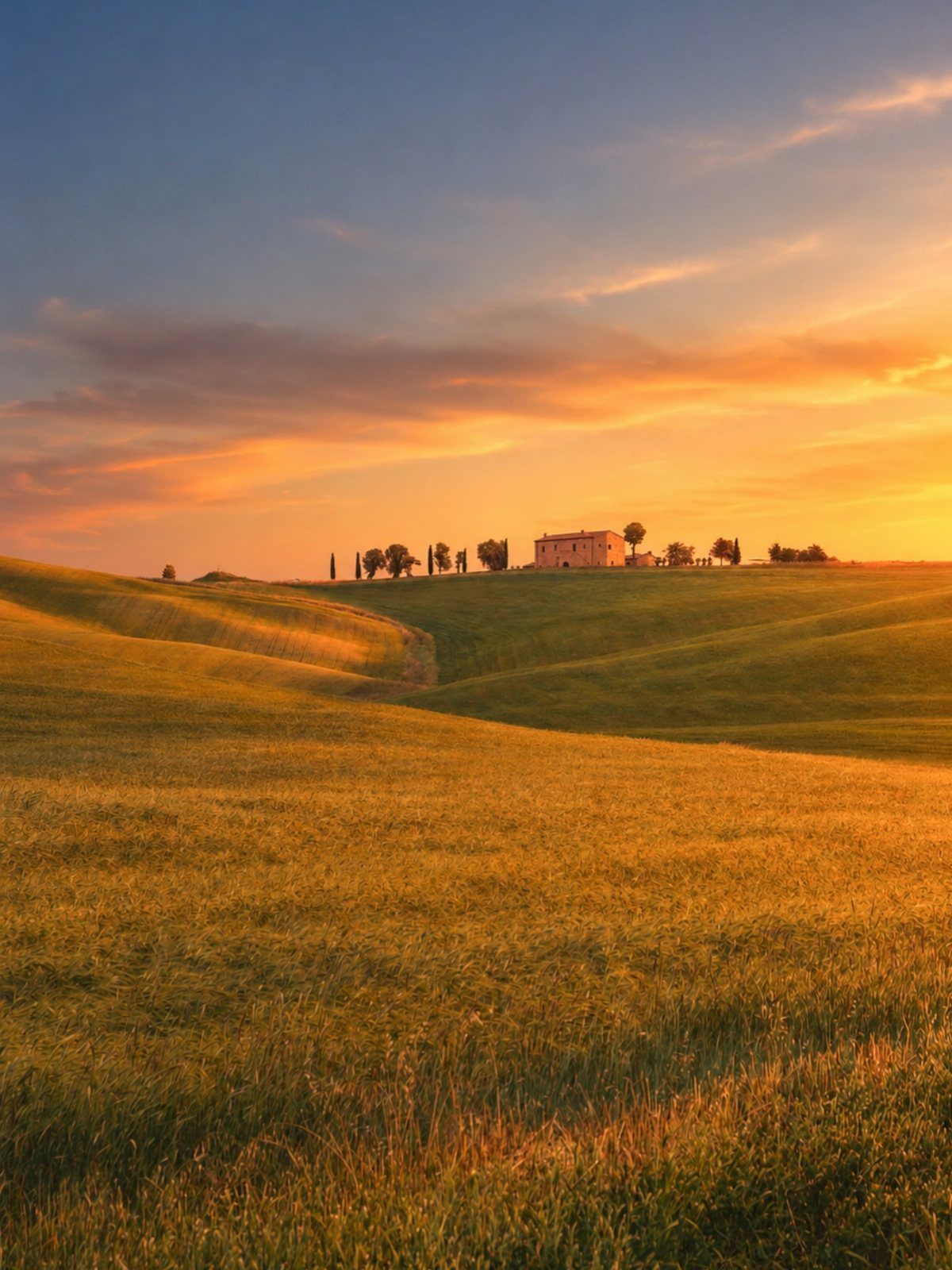 28 Beautiful Places to Travel Around the World 6 Rolling golden hills with a stone house and cypress trees at sunset.