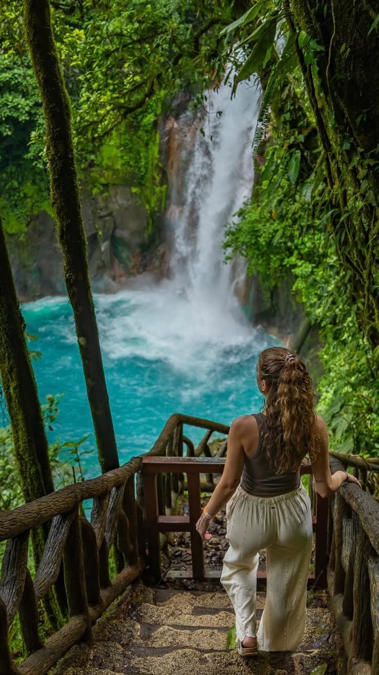 28 Beautiful Places to Travel Around the World 11 Woman looking at a tropical waterfall cascading into a turquoise pool in Costa Rica