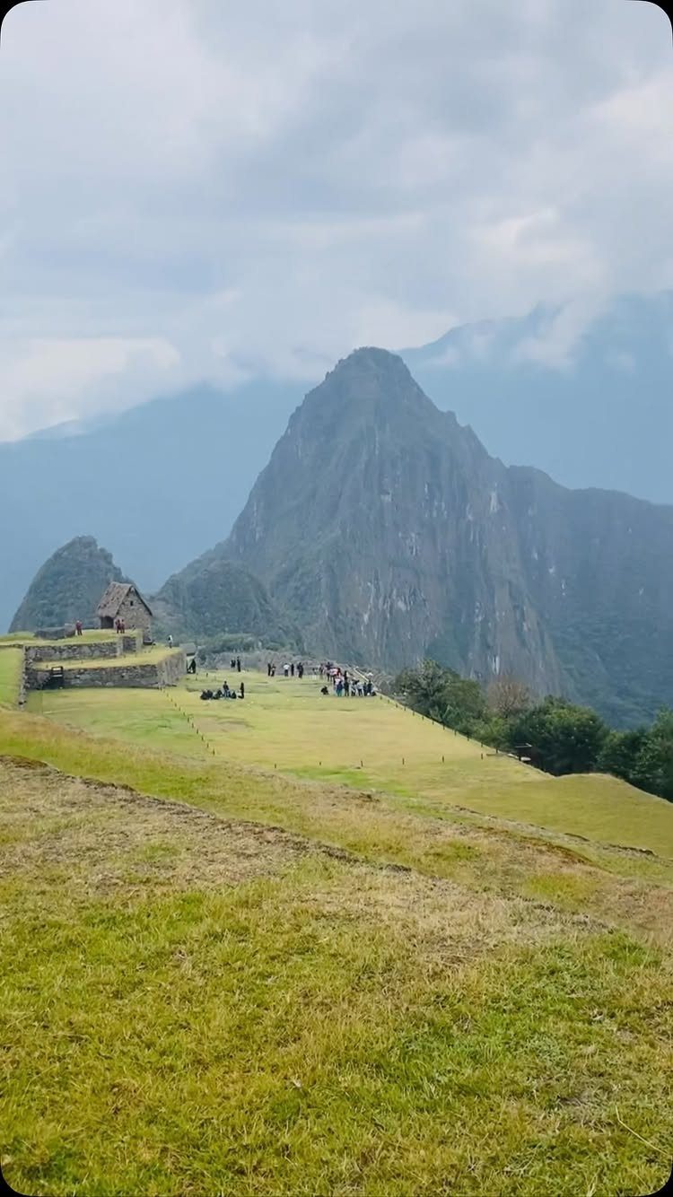 28 Beautiful Places to Travel Around the World 15 Machu Picchu ruins on a green plateau with a steep mountain peak behind.