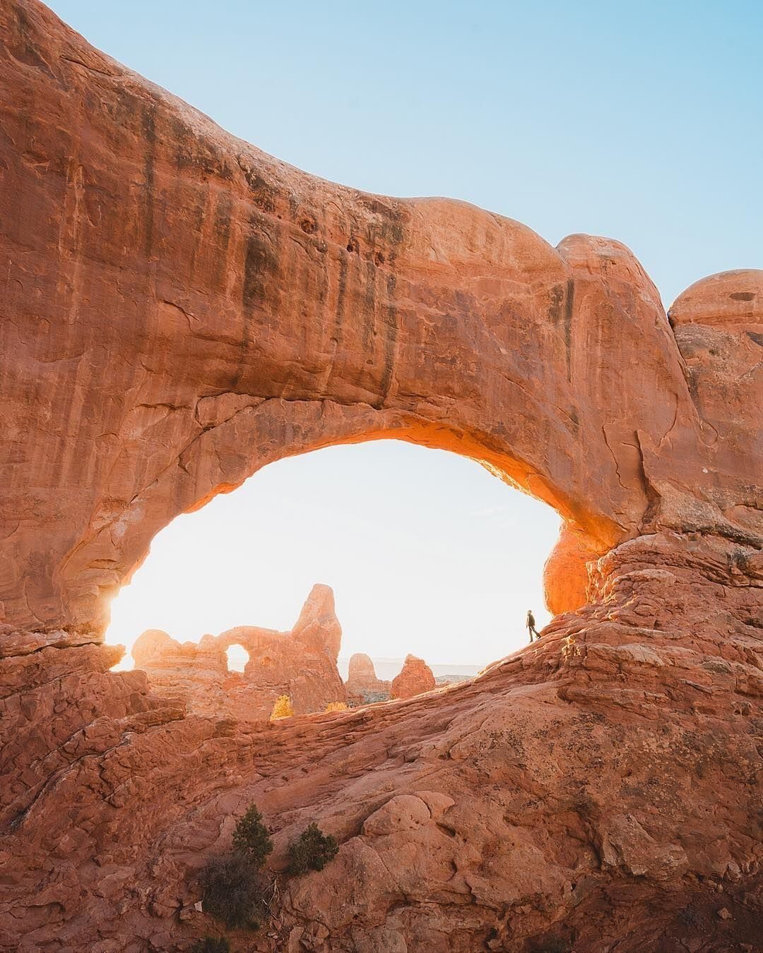 28 Beautiful Places to Travel Around the World 27 Massive red sandstone natural arch with a small person standing beneath it.