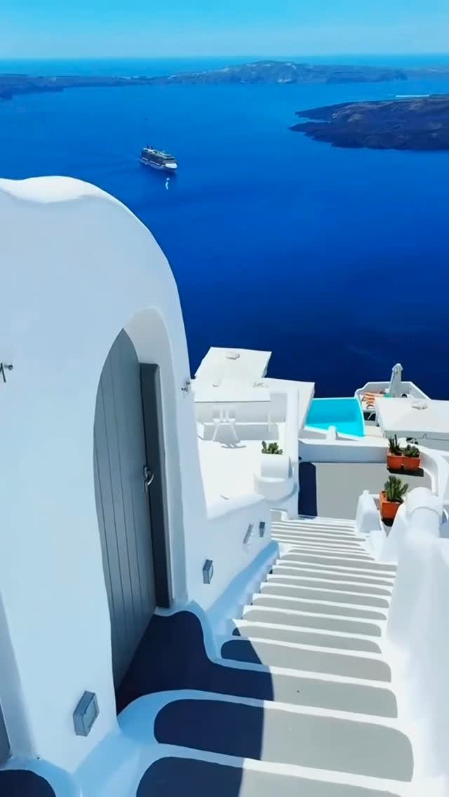 28 Beautiful Places to Travel Around the World 14 Whitewashed curved buildings and stairs overlooking a deep blue sea in Santorini.