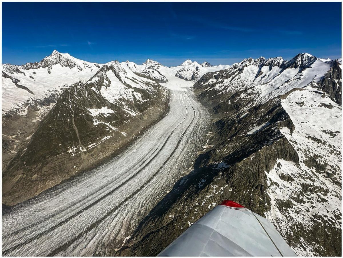 Bucket List Switzerland: 13 Scenic Places and Experiences 3 Massive glacier flowing between snow-capped mountain peaks under a clear blue sky.