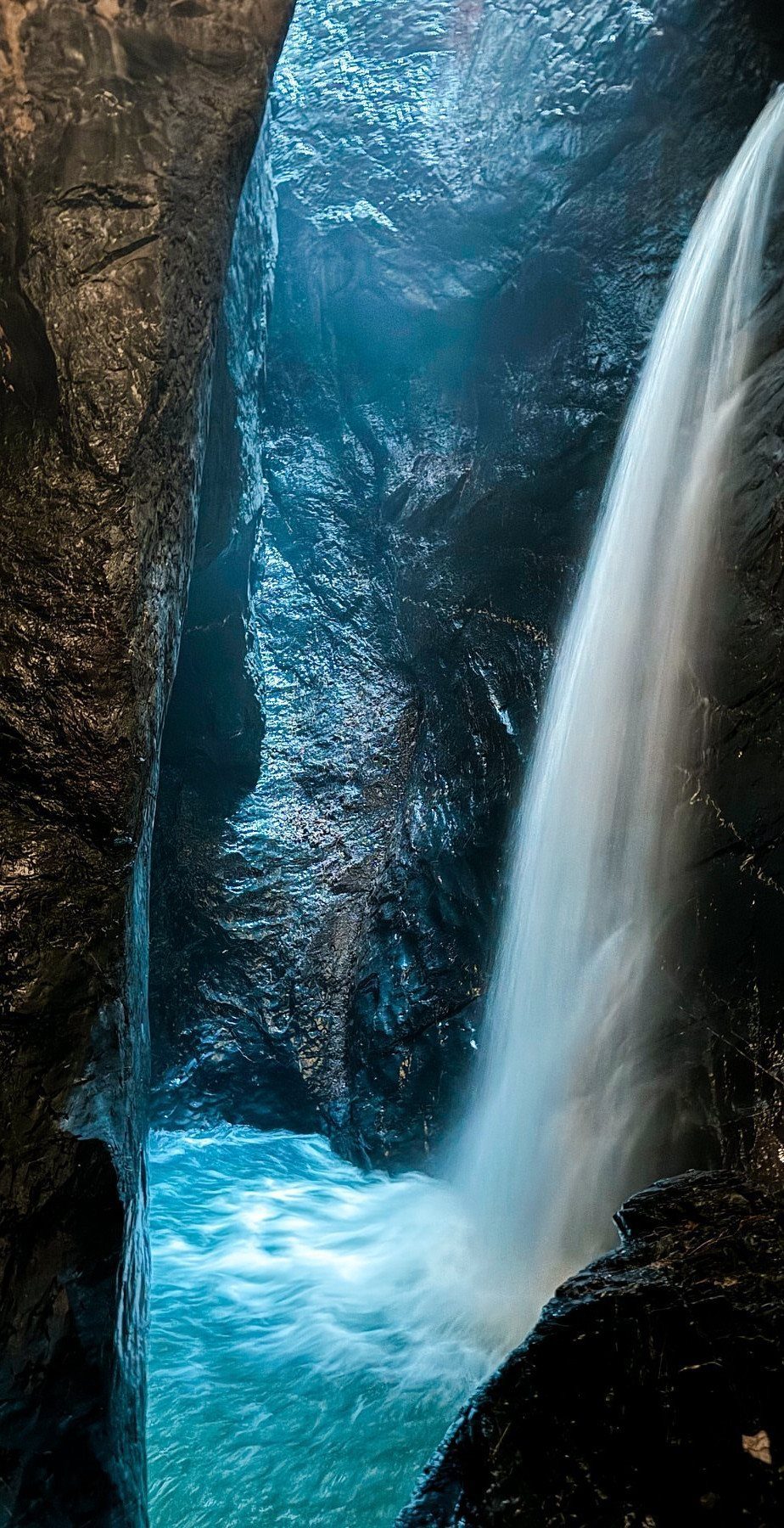 Bucket List Switzerland: 13 Scenic Places and Experiences 13 Waterfall cascading down dark canyon walls into a bright turquoise pool of water.