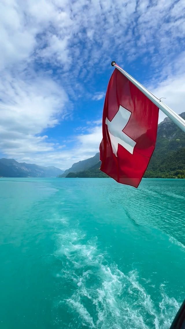 Bucket List Switzerland: 13 Scenic Places and Experiences 11 Swiss flag fluttering over turquoise lake water with mountains in the background