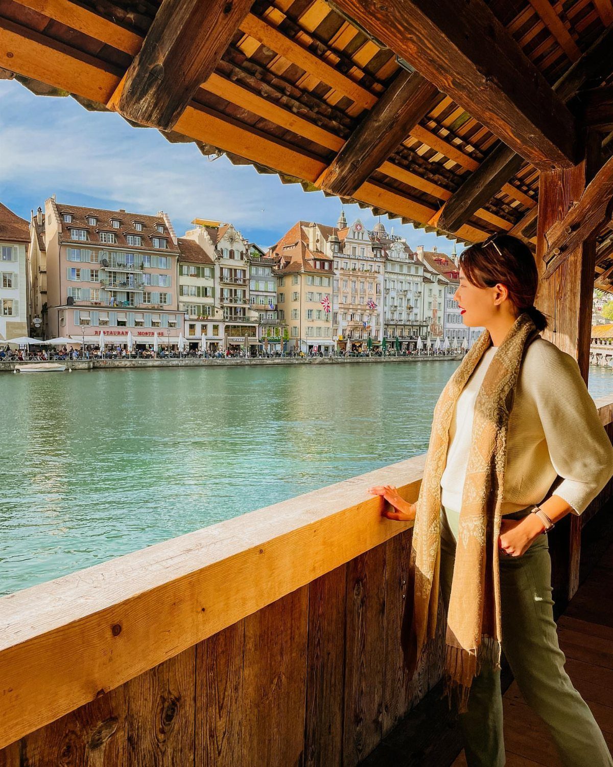 Bucket List Switzerland: 13 Scenic Places and Experiences 1 Woman on the Chapel Bridge looking at colorful buildings across Lake Lucerne