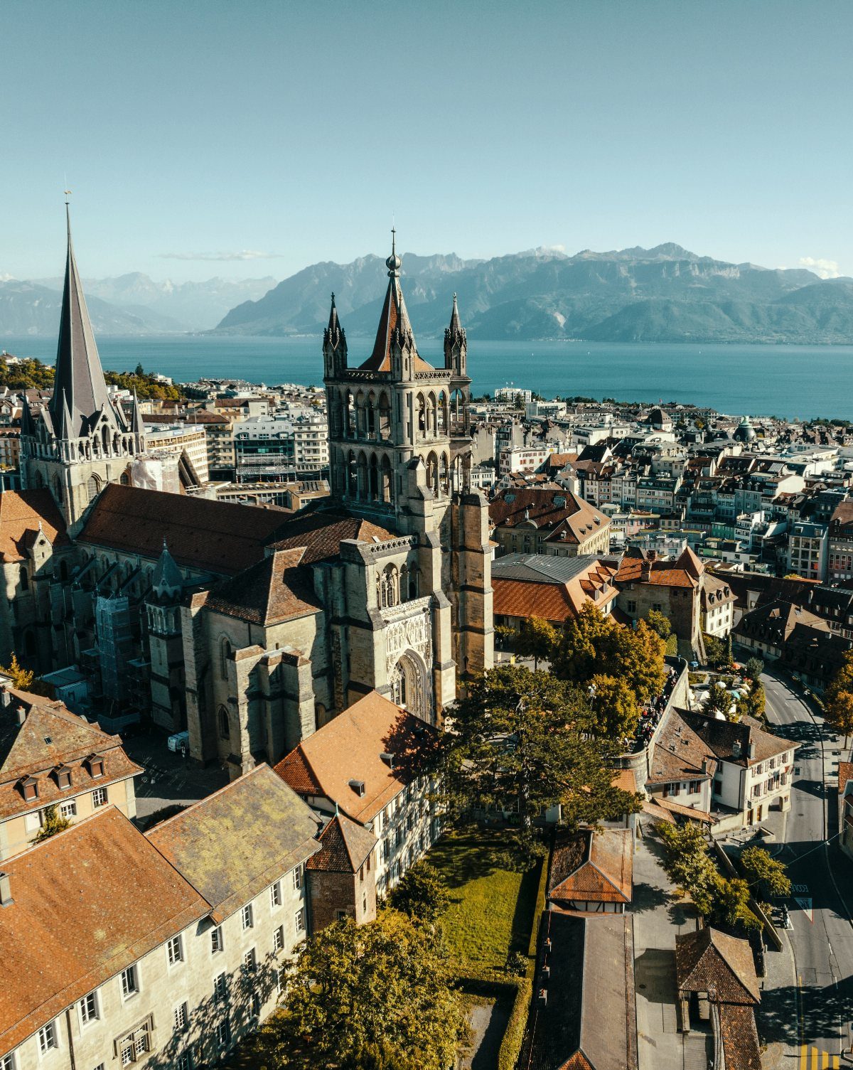 Bucket List Switzerland: 13 Scenic Places and Experiences 2 Lausanne city skyline featuring a grand stone cathedral overlooking Lake Geneva and mountains.