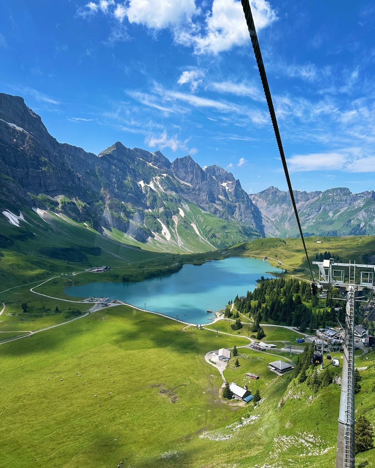 Bucket List Switzerland: 13 Scenic Places and Experiences 12 Turquoise alpine lake surrounded by green meadows and jagged snow-capped mountains.