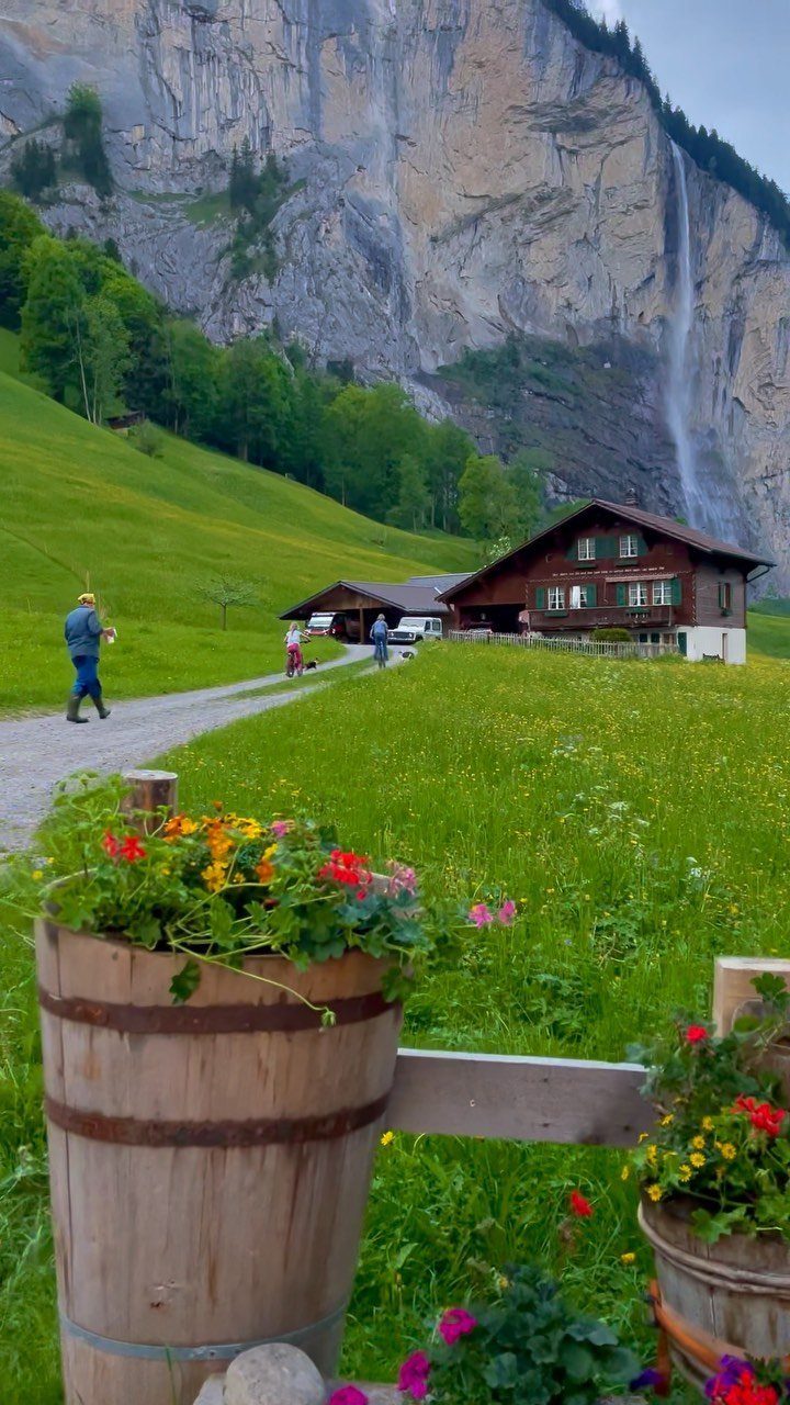 Bucket List Switzerland: 13 Scenic Places and Experiences 4 Staubbach Falls cascading down a cliff behind a traditional Swiss chalet and flower barrels.