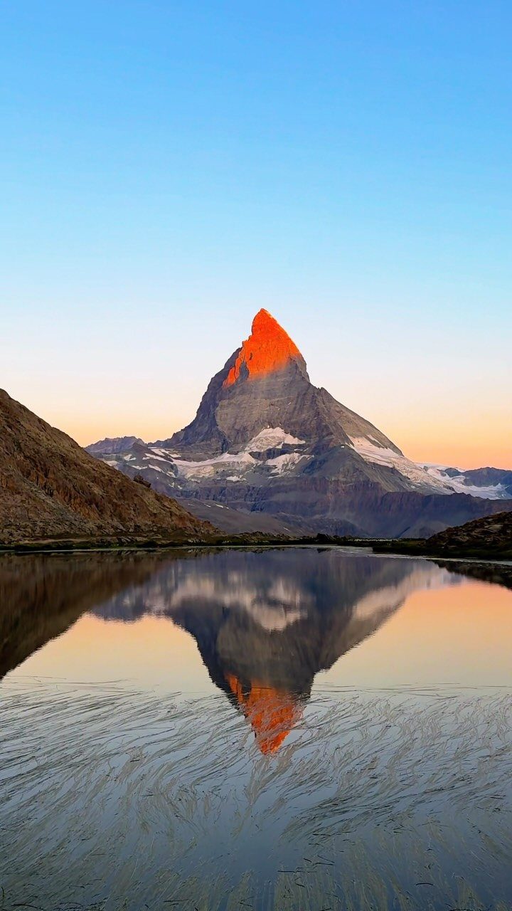 Bucket List Switzerland: 13 Scenic Places and Experiences 9 Matterhorn mountain peak reflecting in a calm lake during a golden sunrise