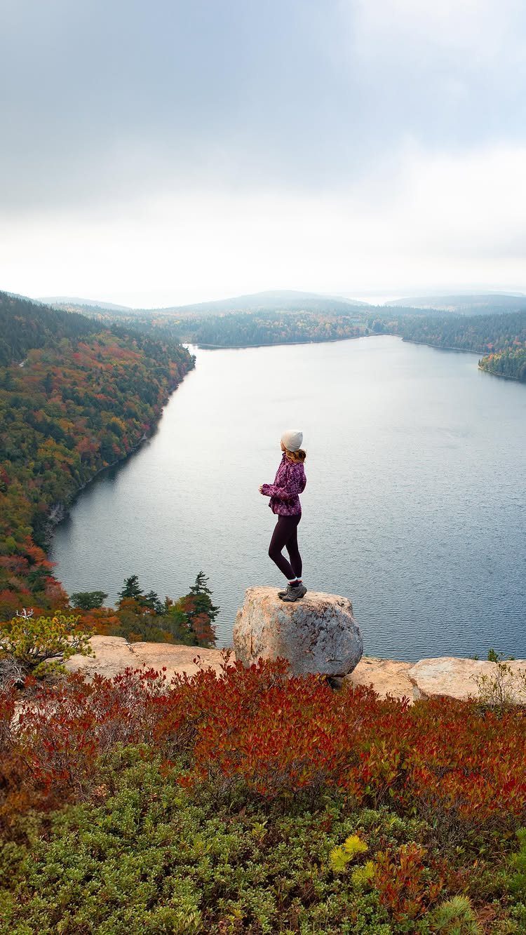 Bucket List Travel Destinations in the USA: 33 Ideas 14 Person standing on a rocky cliff overlooking a lake and autumn forests.