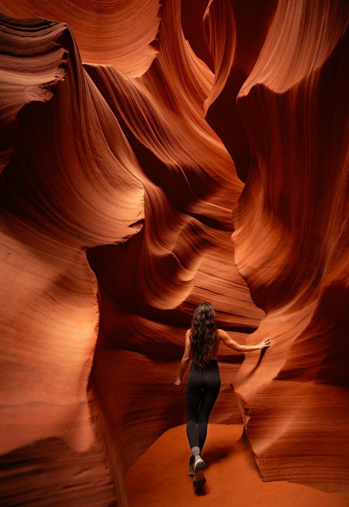 Bucket List Travel Destinations in the USA: 33 Ideas 20 Woman walking through the flowing orange sandstone walls of Antelope Canyon slot canyon.