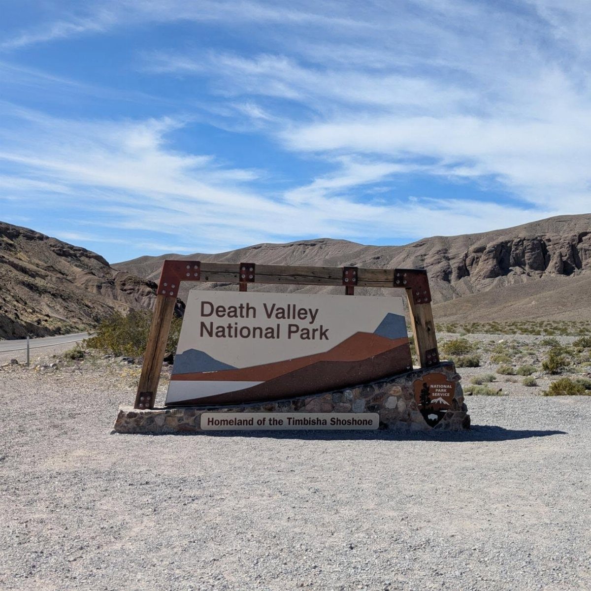 Bucket List Travel Destinations in the USA: 33 Ideas 18 Death Valley National Park entrance sign in a desert landscape with brown mountains.