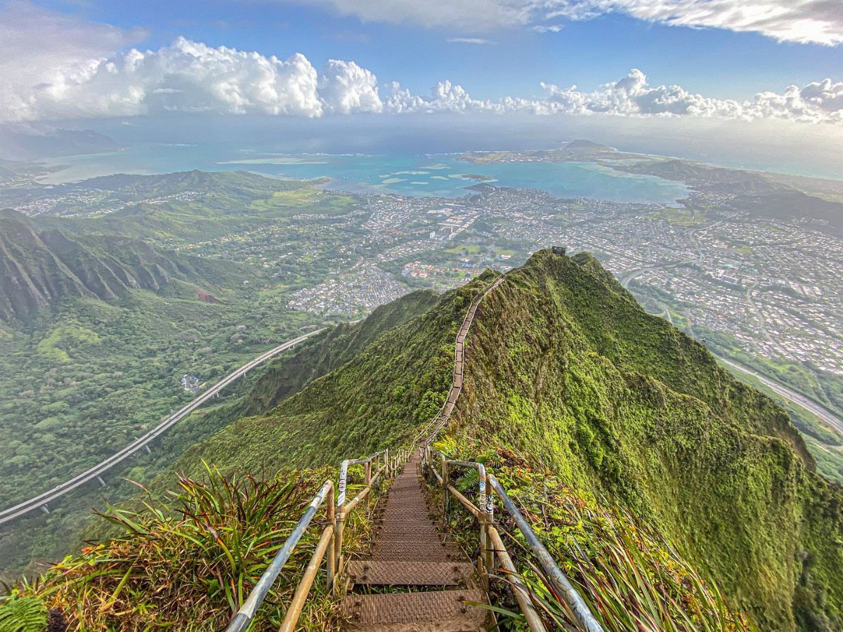 Bucket List Travel Destinations in the USA: 33 Ideas 25 Metal stairs climbing a lush green mountain ridge overlooking a coastal city.