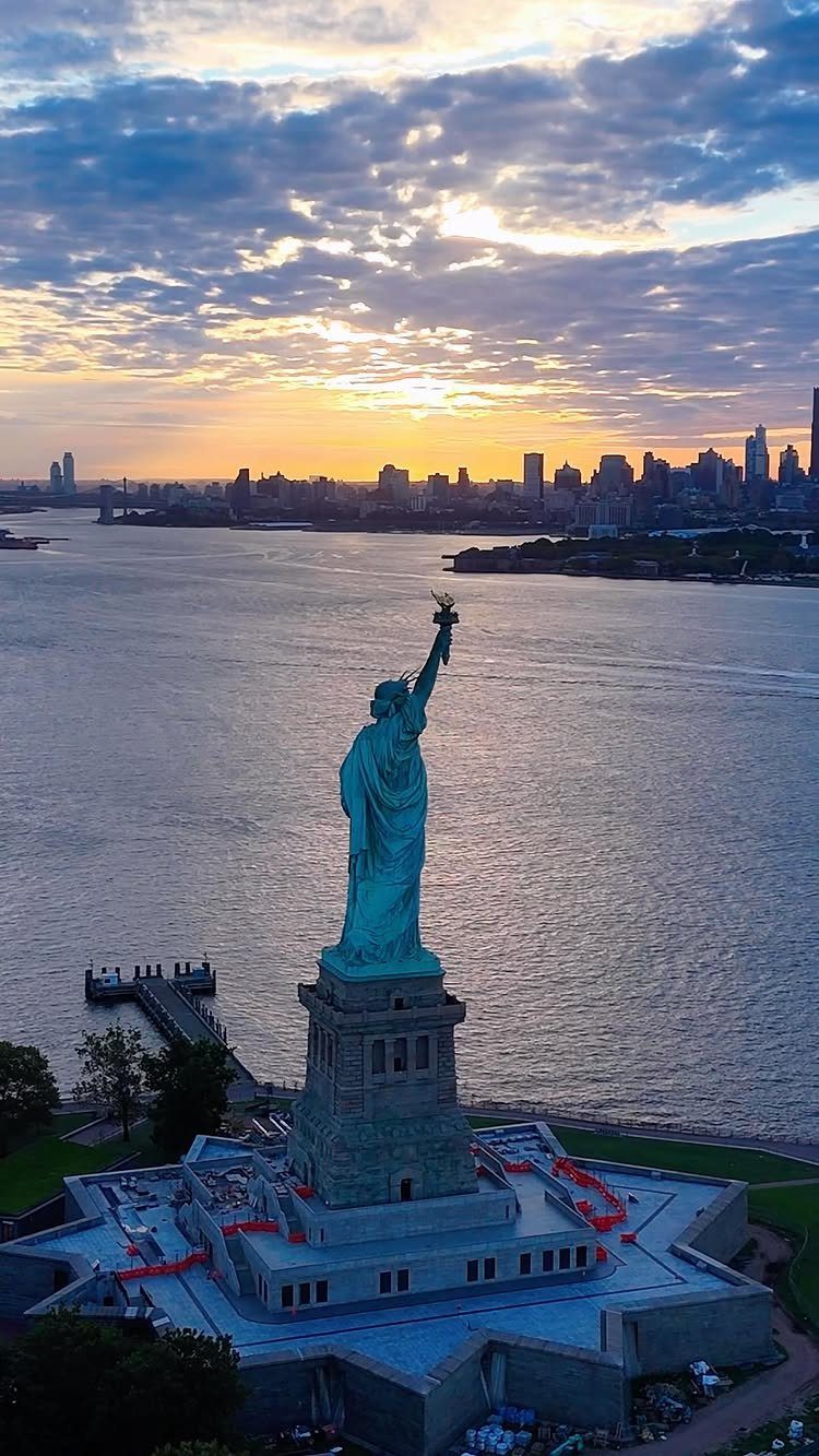 Bucket List Travel Destinations in the USA: 33 Ideas 22 Statue of Liberty on its pedestal with New York City skyline at sunset