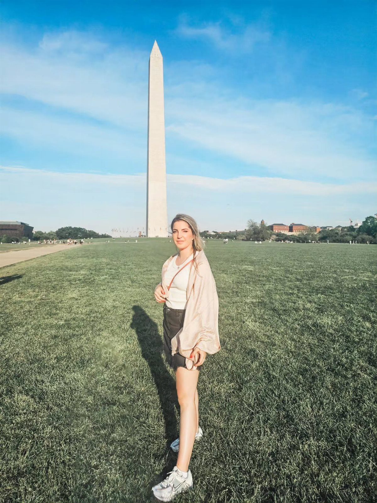 Bucket List Travel Destinations in the USA: 33 Ideas 3 Woman standing in a grassy field with the Washington Monument in the background.