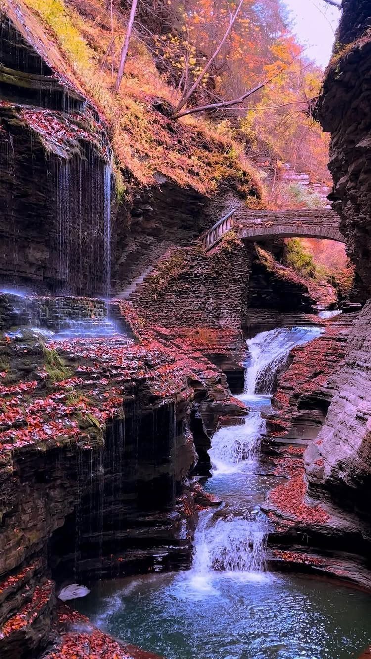 Bucket List Travel Destinations in the USA: 33 Ideas 9 Cascading waterfalls in a rocky gorge surrounded by vibrant autumn foliage and a bridge.
