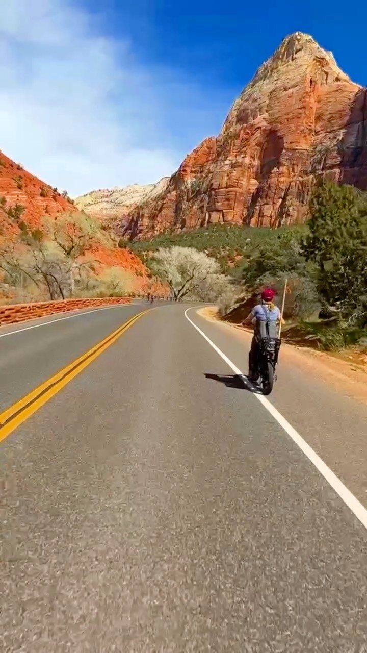 Bucket List Travel Destinations in the USA: 33 Ideas 17 Person standing on a road facing towering red rock cliffs in Zion National Park