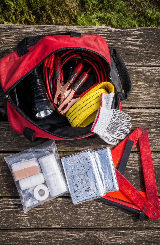 A roadside emergency kit with various supplies in a car trunk.