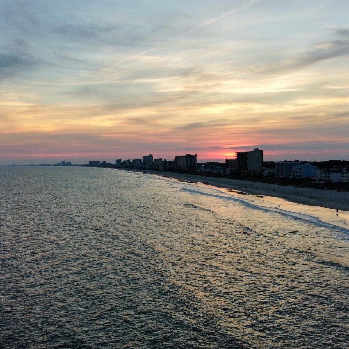 16 Cheap Pretty Places to Travel on a Tight Budget 11 Coastal beach and ocean skyline under a colorful sunset sky with gentle waves.