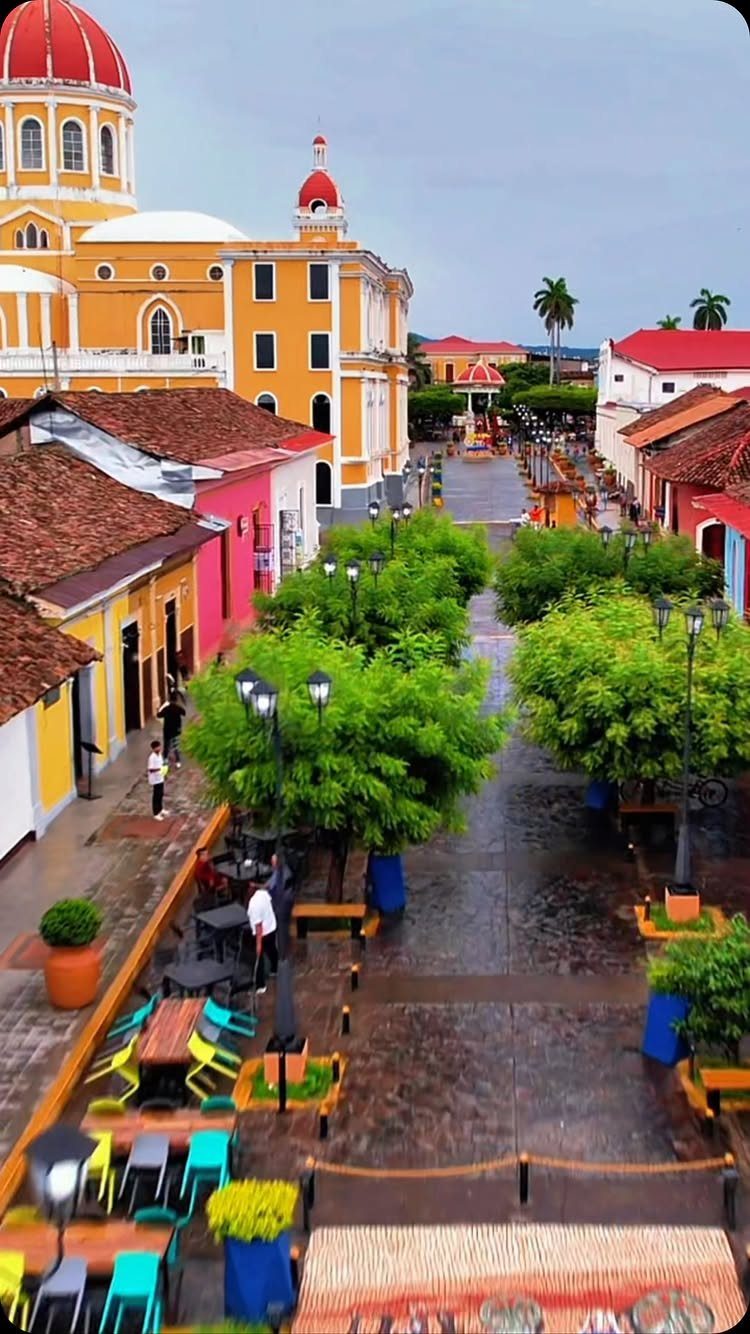 16 Cheap Pretty Places to Travel on a Tight Budget 8 Colorful colonial street with a yellow cathedral and red dome under a grey sky.