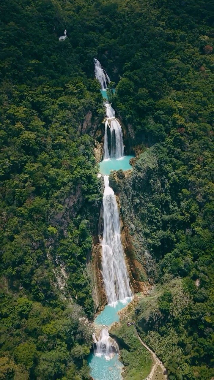16 Cheap Pretty Places to Travel on a Tight Budget 9 Tiered waterfalls cascading down a lush green mountain into turquoise blue pools.