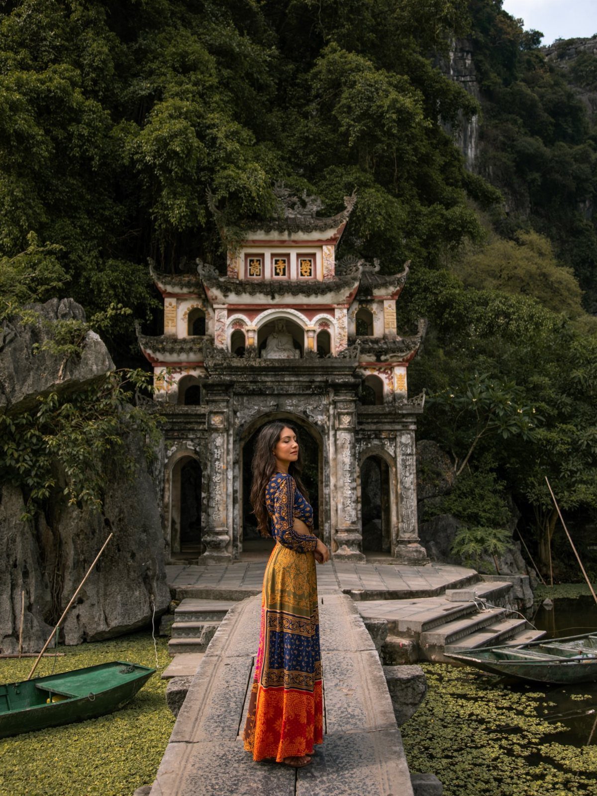16 Cheap Pretty Places to Travel on a Tight Budget 13 Woman in colorful dress standing before an ornate temple nestled in green mountains
