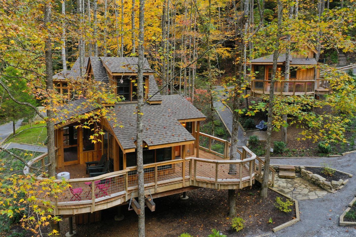 16 Cheap Pretty Places to Travel on a Tight Budget 16 Wooden cabins with decks nestled in a forest with yellow autumn leaves.