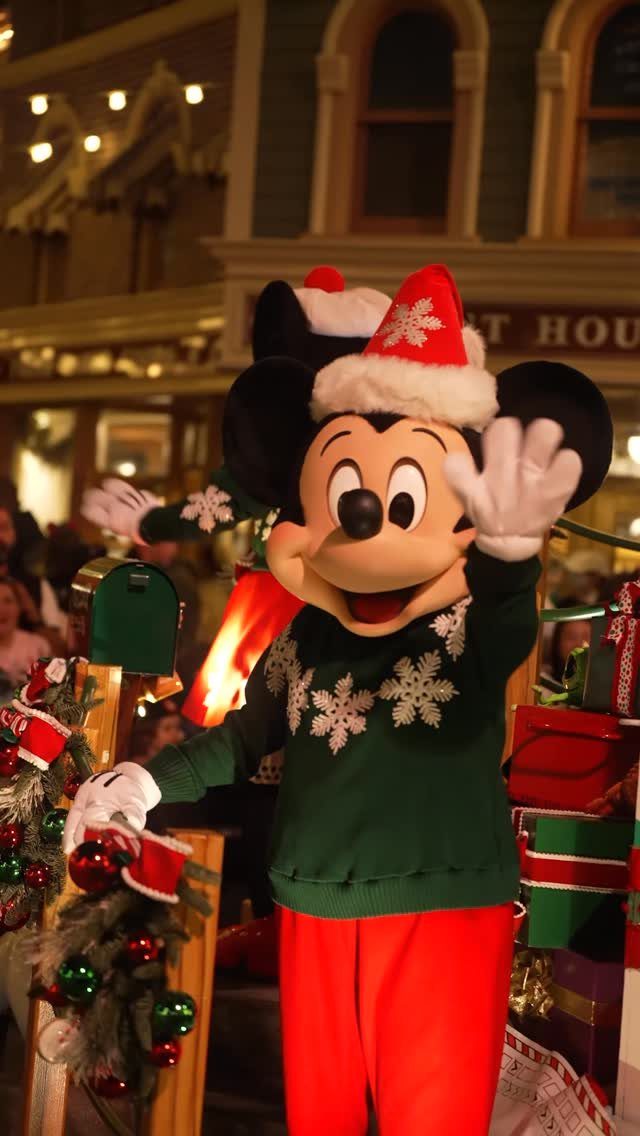 14 Christmas Places to Visit for Holiday Lights and Markets 9 Mickey Mouse in Christmas attire standing among festive decorations and wrapped gifts.
