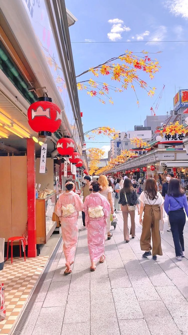 12 Cities to Visit in the U.S. and Abroad for 2026 12 People walking through a Japanese city street with red lanterns and autumn leaves.