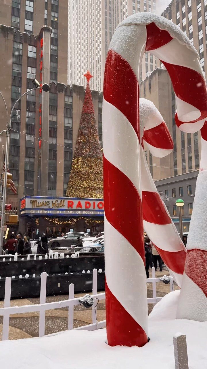 Giant red and white candy cane decoration with a Christmas tree and skyscrapers.