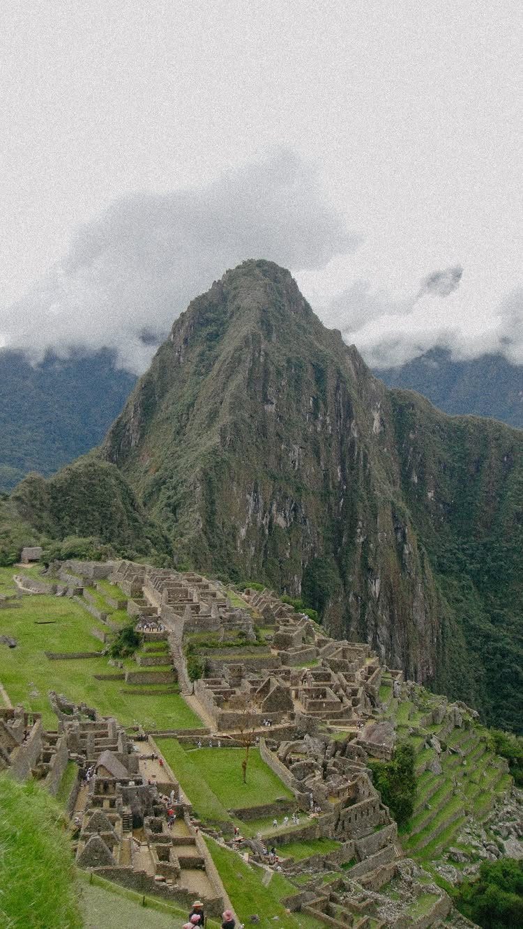 Ancient stone ruins of Machu Picchu with a steep mountain peak behind.