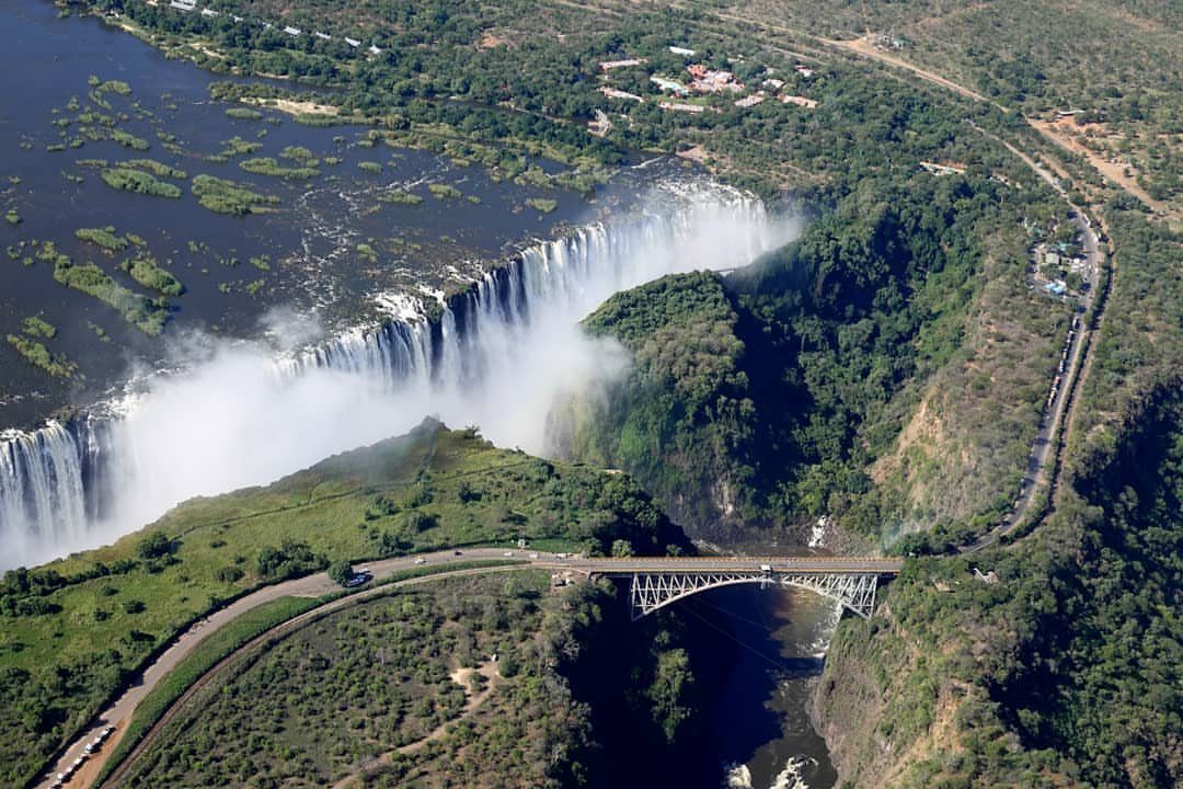 Victoria Falls cascading into a deep gorge with a steel bridge nearby.