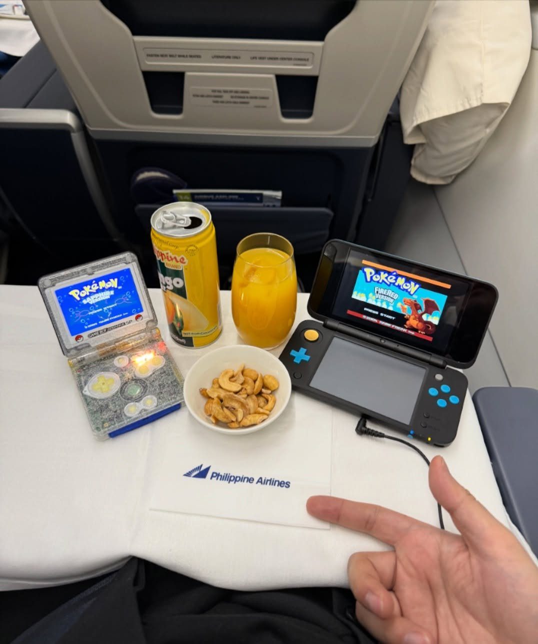 Nintendo Switch playing Pokémon on an airplane tray with snacks and drinks
