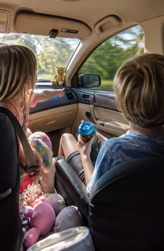 Children playing I Spy in a sunny car interior.