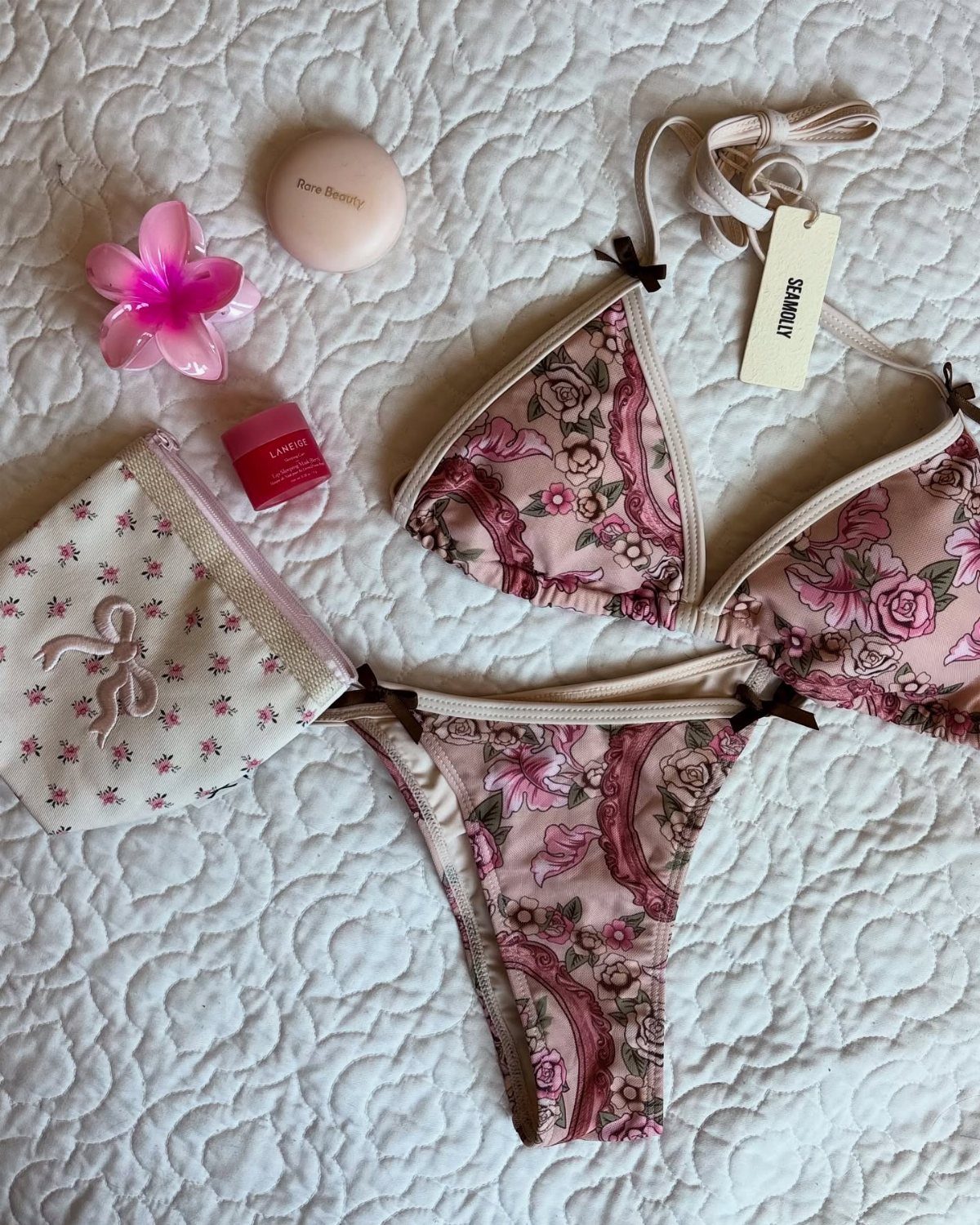 How to Pack for a 3 Week Trip: 7 Packing Ideas 3 Pink floral print bikini set with cosmetics on a white quilted background