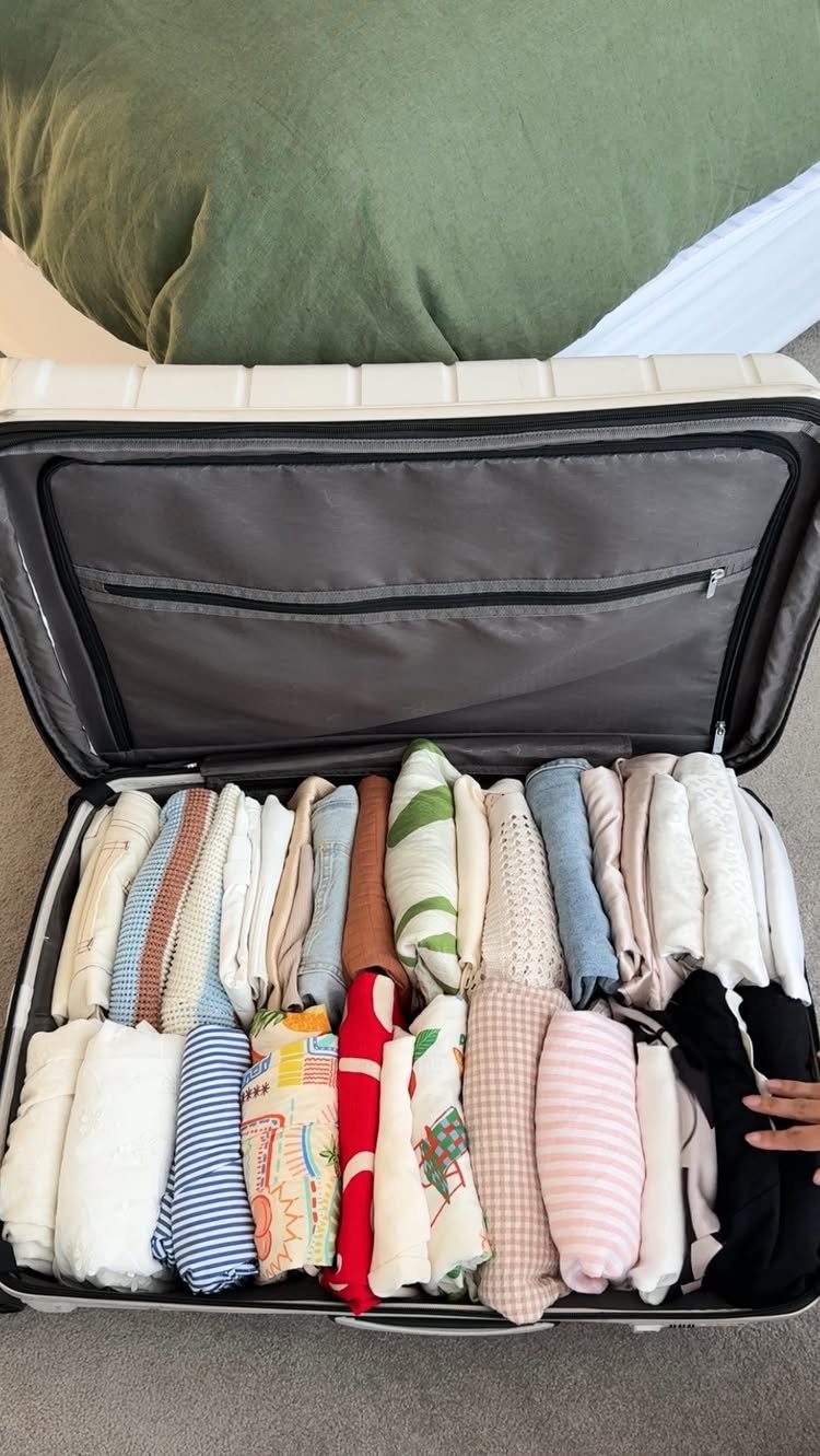 How to Pack for a 3 Week Trip: 7 Packing Ideas 6 Open white suitcase packed with neatly rolled and folded colorful clothing on carpet.